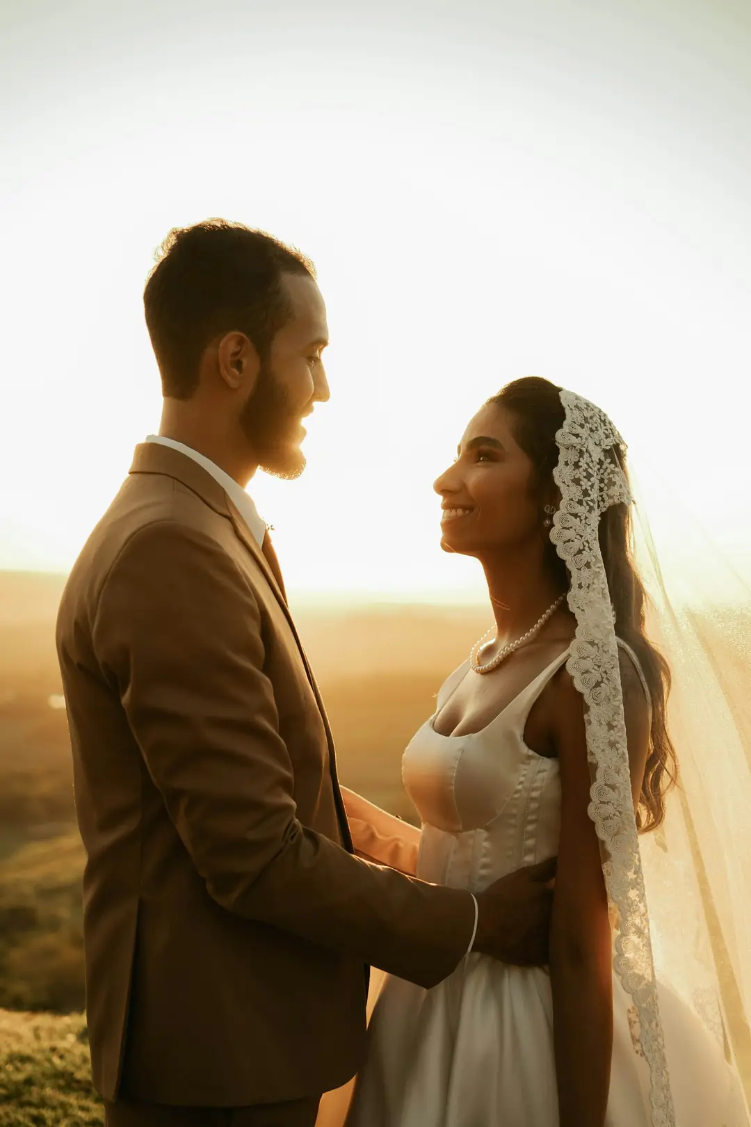 Una pareja de novios se mira al atardecer, en el campo